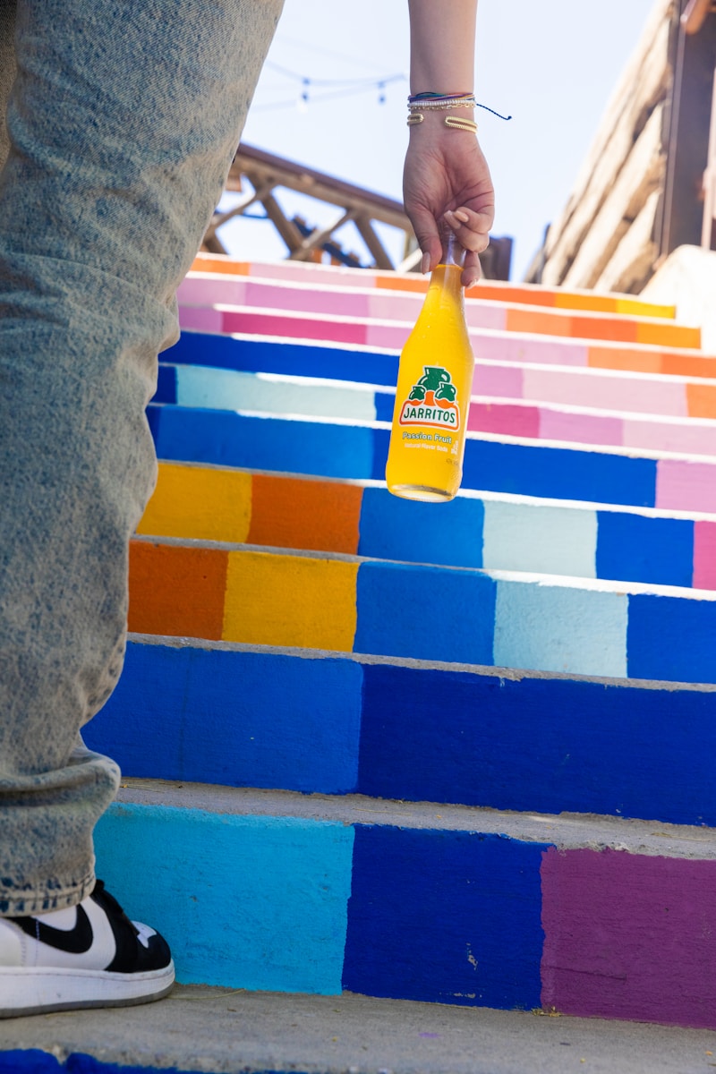 A person standing on a colorful staircase with a bottle of mustard